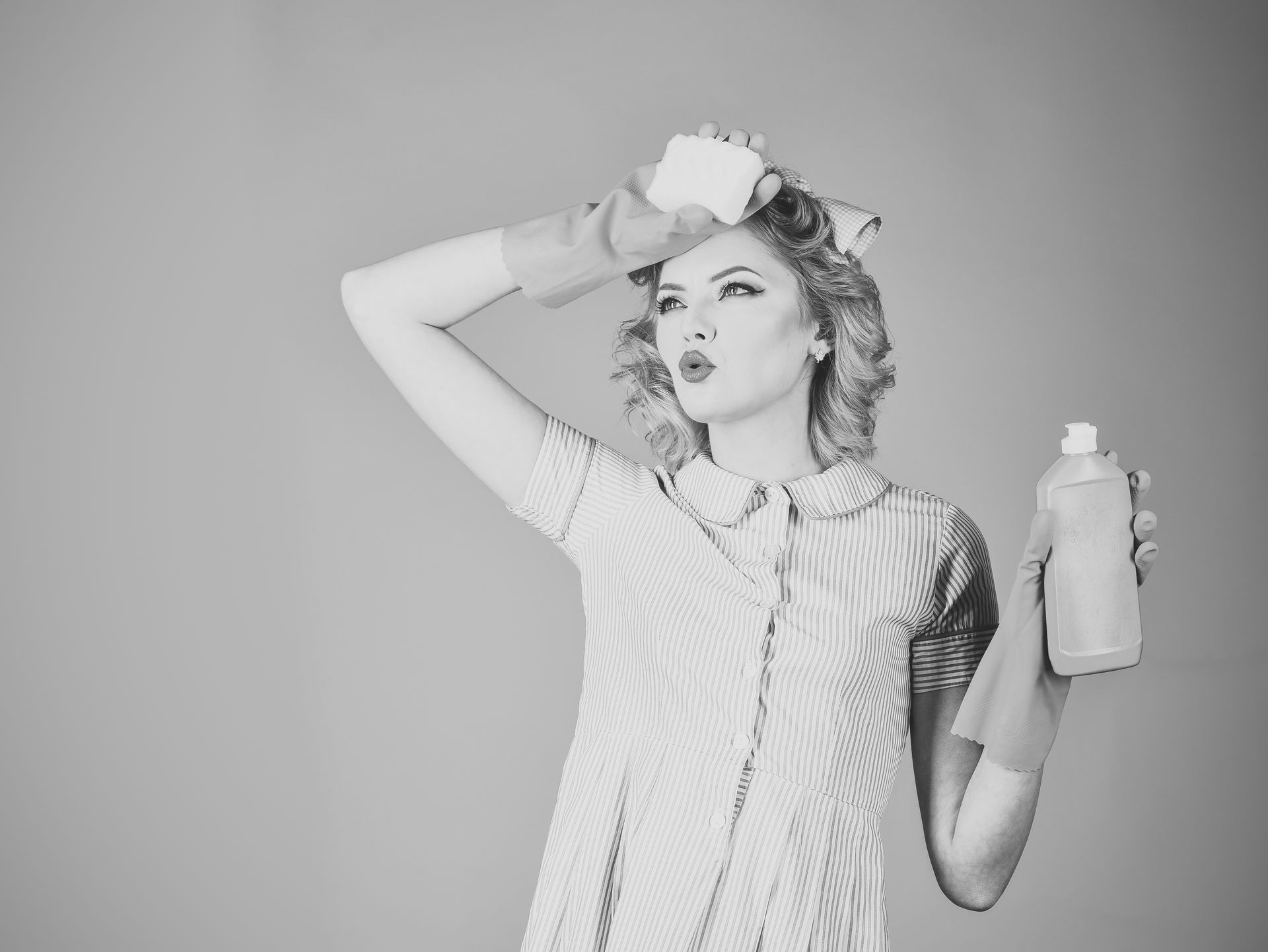 Housekeeper in uniform with clean spray, sponge. Retro woman cleaner on pink background. Cleanup, cleaning services, wife, gender. Cleaning, retro style, purity. Pinup woman hold soup bottle, sponge.